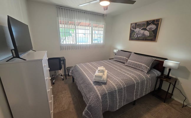 Black oak platform bed frame inside a furnished room rental